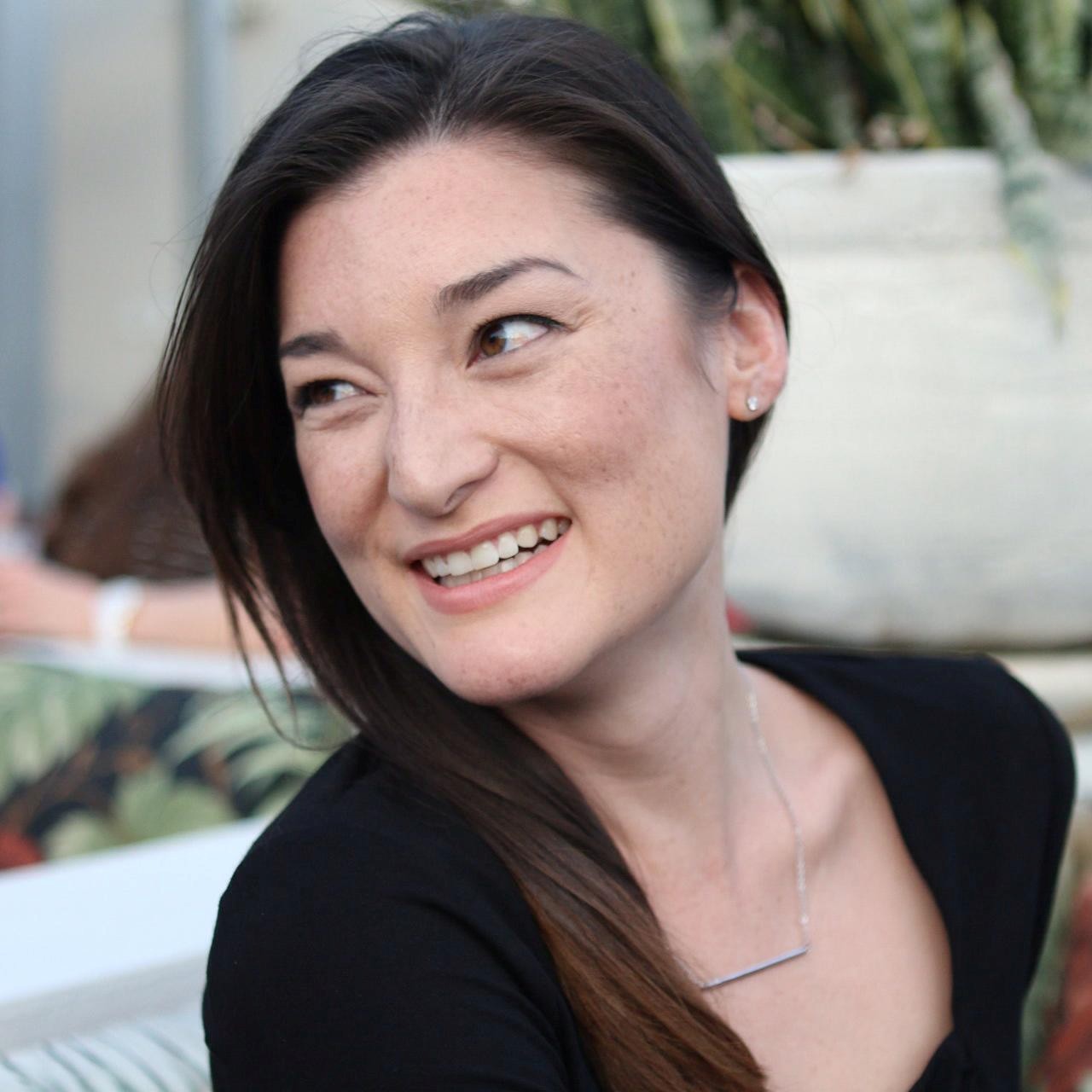 Debbie Willis is sitting in a black shirt, smiling and looking over her right shoulder away from the camera